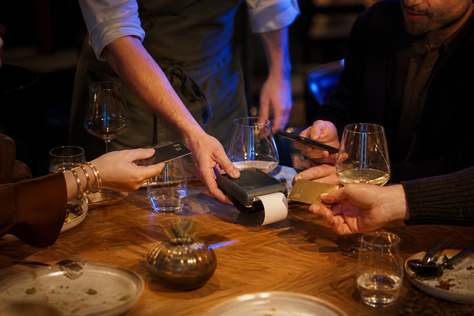 Guests settling a shared restaurant bill with several payment methods